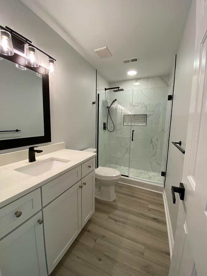 Bathroom remodel after photo: marble walk-in shower, white vanity, and matte black fixtures