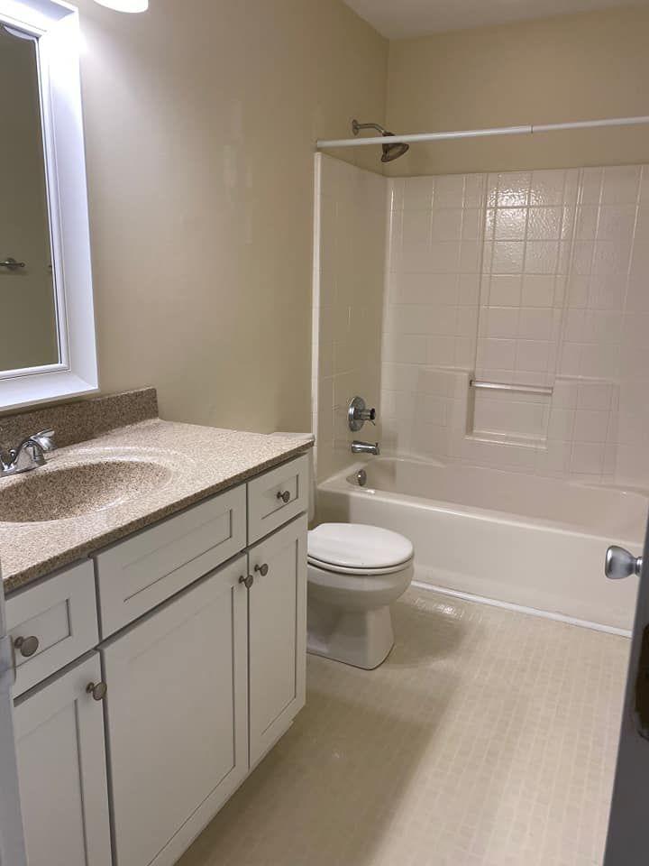 Bathroom before photo showing outdated bathtub, surround, and laminate countertop