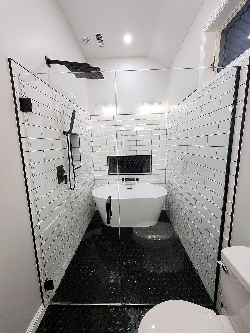 Luxury bathroom remodel with freestanding tub, black hex tile shower floor, and matte black fixtures