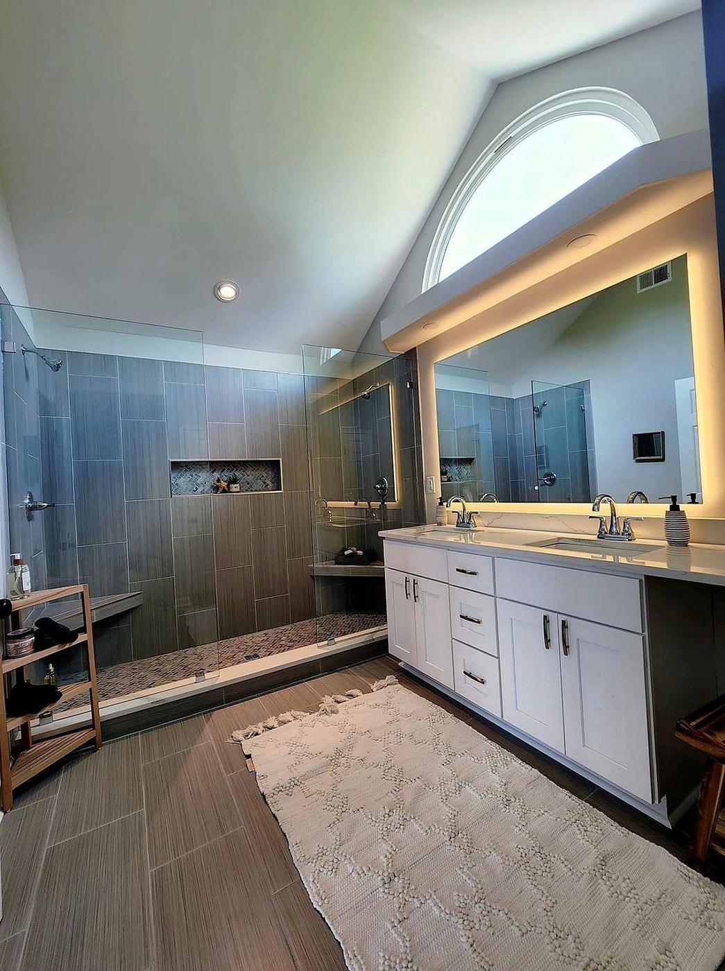 Bathroom remodel with tiled walk-in shower, LED vanity mirror, and integrated bathtub surround