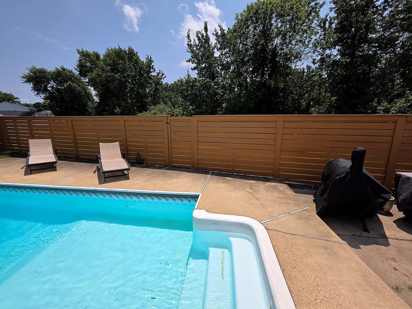Composite privacy fence installation beside residential pool deck and lounge area