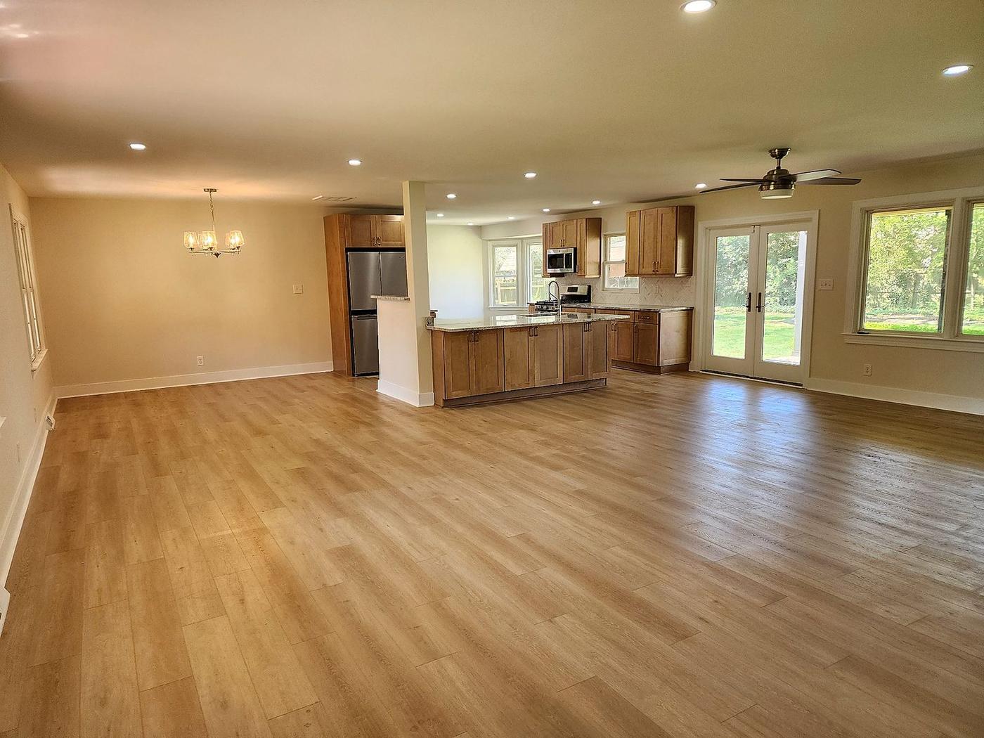 Open-concept full home renovation with new kitchen, wide-plank floors, recessed lighting, and patio doors
