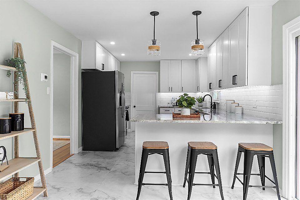 Contemporary kitchen remodel with gray cabinetry, breakfast bar seating, pendant lighting, and subway tile backsplash