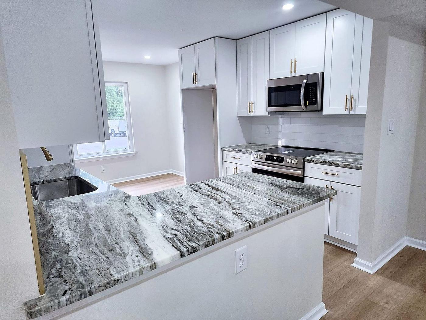 Kitchen remodel with white shaker cabinets, gold hardware, marble countertops, and stainless range