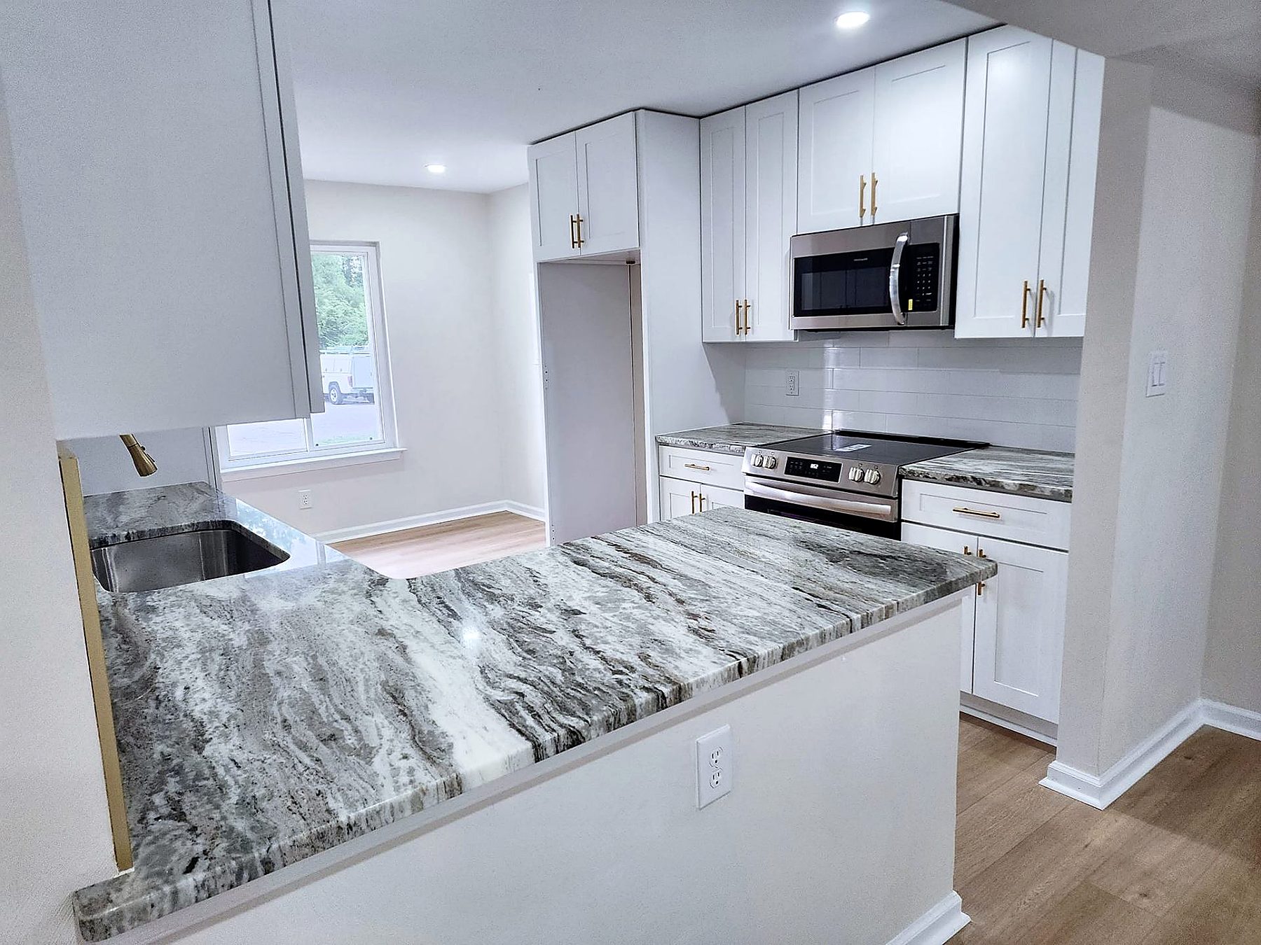 Kitchen remodel with white shaker cabinets, gold hardware, marble countertops, and stainless range