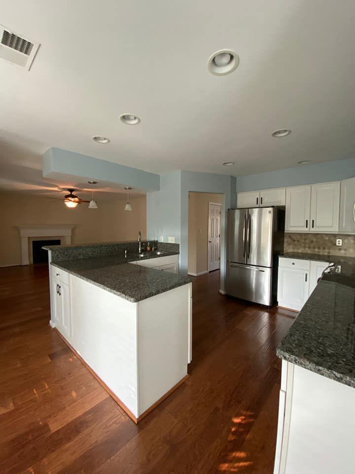 Kitchen before photo showing dated layout, dark countertops, and original cabinets