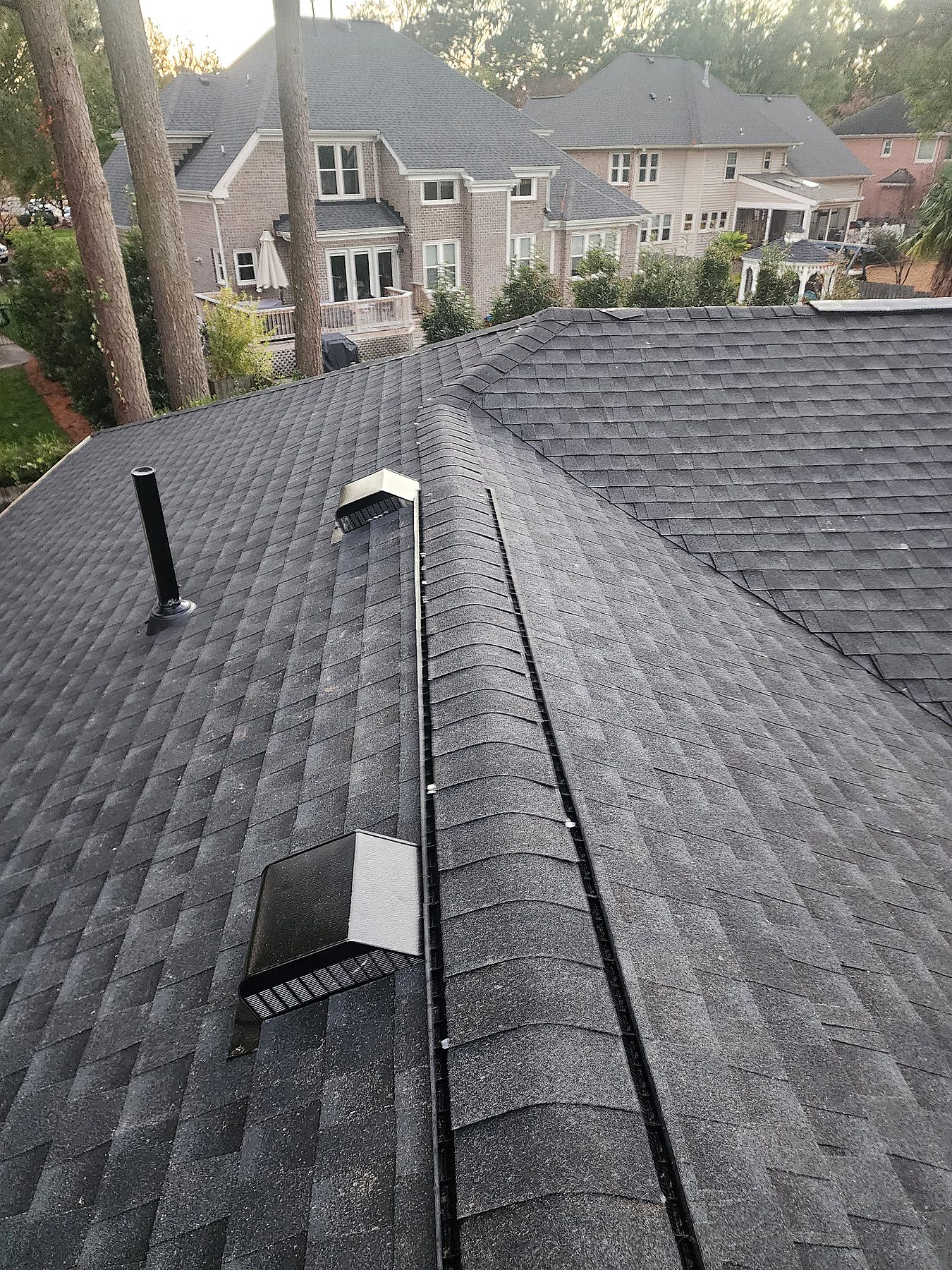 Architectural shingle roof replacement detail showing ridge caps, venting, and clean installation lines