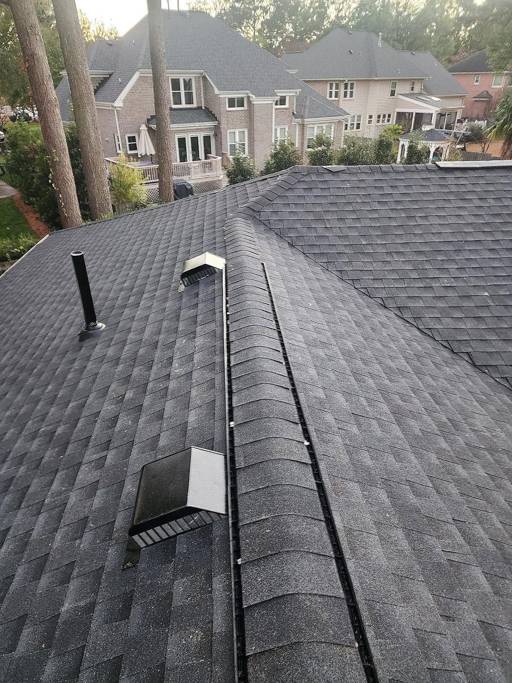 Architectural shingle roof replacement detail showing ridge caps, venting, and clean installation lines